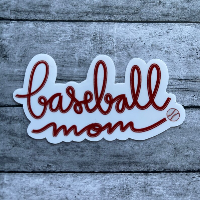 May include: White sticker with red cursive text that says "baseball mom" with a small red baseball graphic.