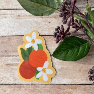 May include: A sticker featuring a cluster of orange fruit with white blossoms and green leaves on a yellow background.
