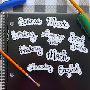 May include: A set of ten white stickers with black cursive lettering for different school subjects. The subjects include: Science, Music, Writing, Language Arts, Social Studies, History, Math, Chemistry, and English.