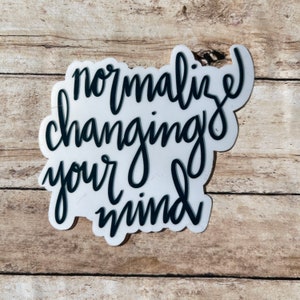 May include: White sticker with black lettering that reads "normalize changing your mind".