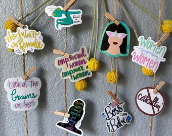 May include: A collection of colorful stickers with empowering messages about women. The stickers feature phrases like "The future is female", "Empowered women empower women", "Women supporting women", and "Boss Babe".