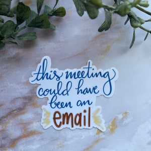 Pode incluir: Etiqueta branca com texto azul que diz "this meeting could have been an email" com texto marrom que diz "email" e detalhes de glitter dourado.