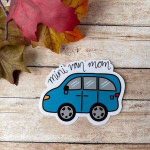 May include: A blue minivan sticker with the text "mini van mom" in white cursive writing.