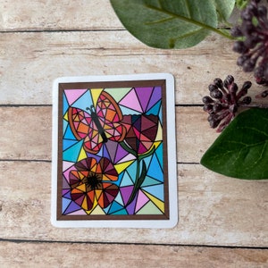 May include: A stained glass style illustration of a butterfly and flower in a brown frame. The butterfly is orange, yellow, and red. The flower is orange, red, and brown. The background is a mix of blue, purple, pink, and yellow.