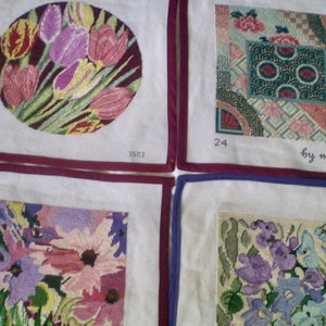May include: Four needlepoint squares with floral designs. One features tulips in a circle, another has an Asian-inspired pattern, and the others display various flowers. Each is framed with a colored border.