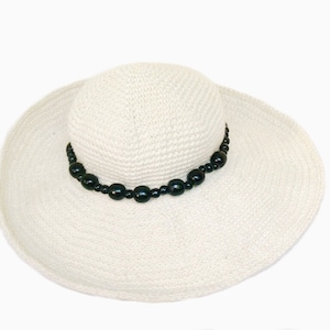 May include: A white straw sun hat with a black beaded trim.