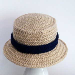 May include: A beige crocheted hat with a wide brim and a navy blue crocheted band around the crown.