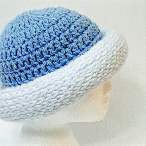 May include: A blue and white crocheted hat with a wide brim. The hat is made with a textured stitch and has a gradient of color from dark blue to light blue.