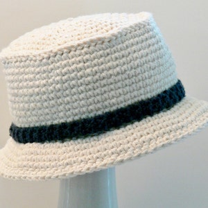 May include: A white crocheted bucket hat with a dark blue and green trim around the crown.
