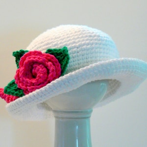 May include: White crocheted sun hat with a pink and green crocheted flower.