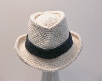 Può includere: Un cappello fedora bianco all'uncinetto con una fascia nera.