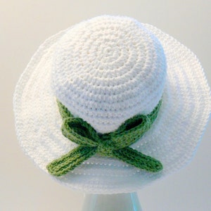 May include: A white crochet sun hat with a green crocheted bow.