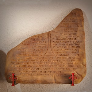 May include: A weathered stone tablet with an inscription in Latin. The inscription includes the words "Cruciala", "Bibic Aquao", "Habibic Foll", "Vica", "Ax Dhorum", "Sagculorio", "Rafugicko", "Pericacao", "Armas", "Fugiur", "Dricang", "Liaw Sacran", "Wonder in Loco", "Que meus pa", "Angustins", "Crescences", "Lunas", "Iro Salus", "Lacas", "Ad Eroplu", "Solis", "Onlibus", "Viris", "Sas", "Sarcguoi", "Euri", "Gradalus", "Quae", "Connel", "Sanguinea", "Issu", "Chrisa", "Toscri", "Peroanarin", "Adcarnesco", "Sourbius", "Iris", "Saus", "Sarcell".