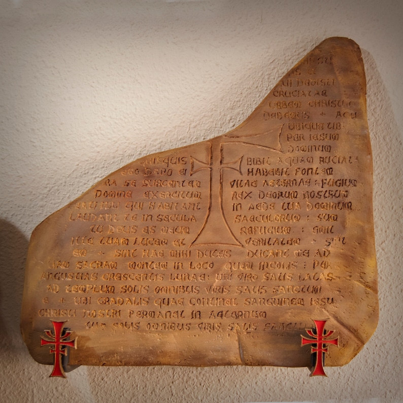 May include: A weathered stone tablet with an inscription in Latin. The inscription includes the words "Cruciala", "Bibic Aquao", "Habibic Foll", "Vica", "Ax Dhorum", "Sagculorio", "Rafugicko", "Pericacao", "Armas", "Fugiur", "Dricang", "Liaw Sacran", "Wonder in Loco", "Que meus pa", "Angustins", "Crescences", "Lunas", "Iro Salus", "Lacas", "Ad Eroplu", "Solis", "Onlibus", "Viris", "Sas", "Sarcguoi", "Euri", "Gradalus", "Quae", "Connel", "Sanguinea", "Issu", "Chrisa", "Toscri", "Peroanarin", "Adcarnesco", "Sourbius", "Iris", "Saus", "Sarcell".