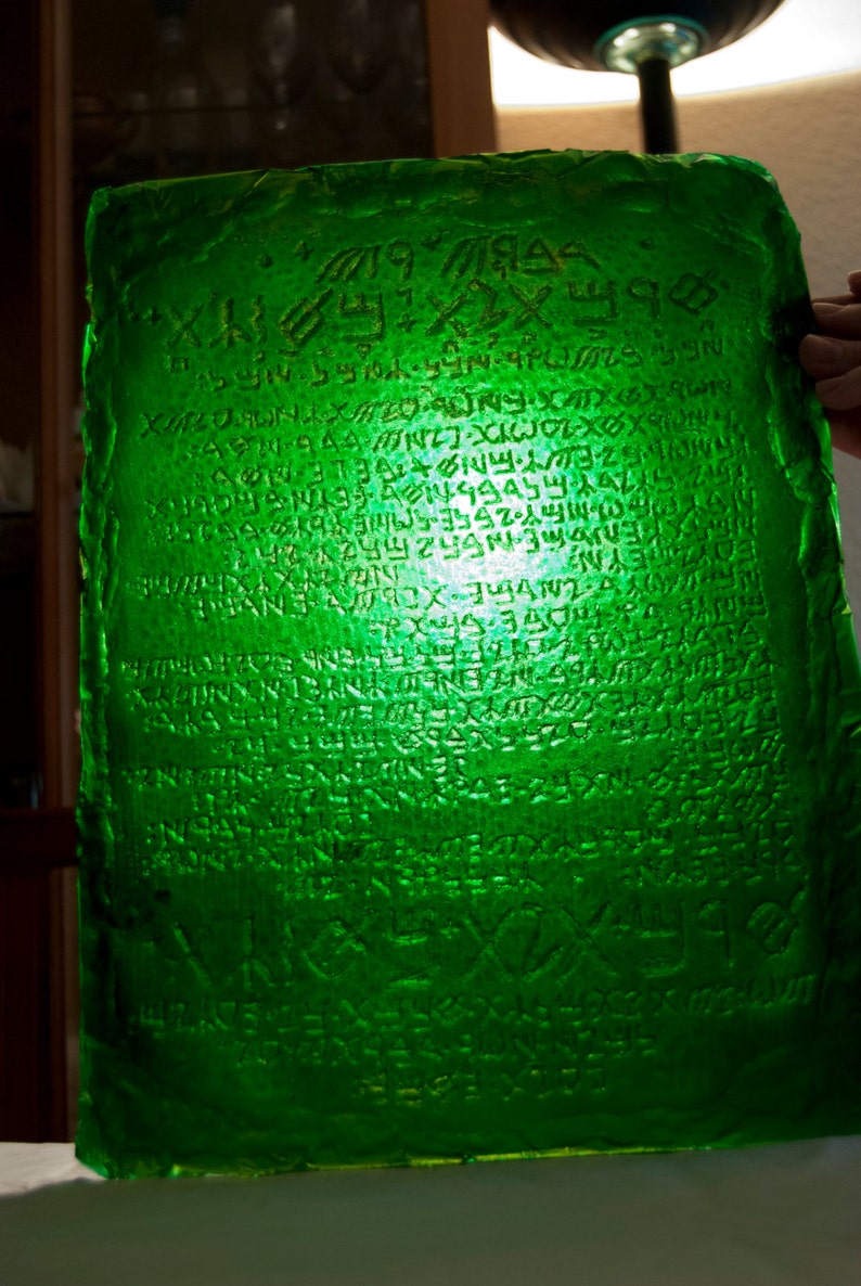 May include: A green glass plaque with an inscription in an unknown language. The inscription is carved into the glass and appears to be ancient.