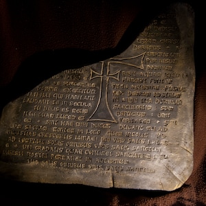 May include: A weathered stone slab with an inscription in Latin. The inscription includes the words "SINC HAE MIHI DUCES" and "CRILAZEOS".