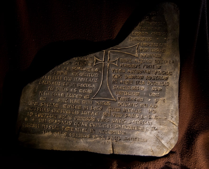 May include: A weathered stone slab with an inscription in Latin. The inscription includes the words "SINC HAE MIHI DUCES" and "CRILAZEOS".