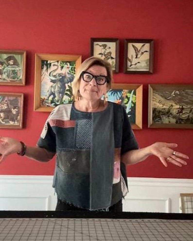 May include: A short-sleeved top constructed from various denim and fabric patches in shades of blue, gray, and white. The garment features a mix of solid panels, striped sections, and textured squares, with a raw, uneven hemline at the bottom edge.