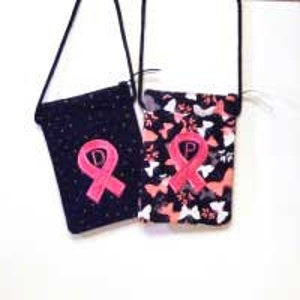 Puede incluir: Dos bolsos bandolera de tela negra con bordado de cinta rosa y estampado de mariposa blanca. Una bolsa tiene un fondo negro con lunares blancos, la otra tiene un estampado de mariposa blanca sobre un fondo negro.