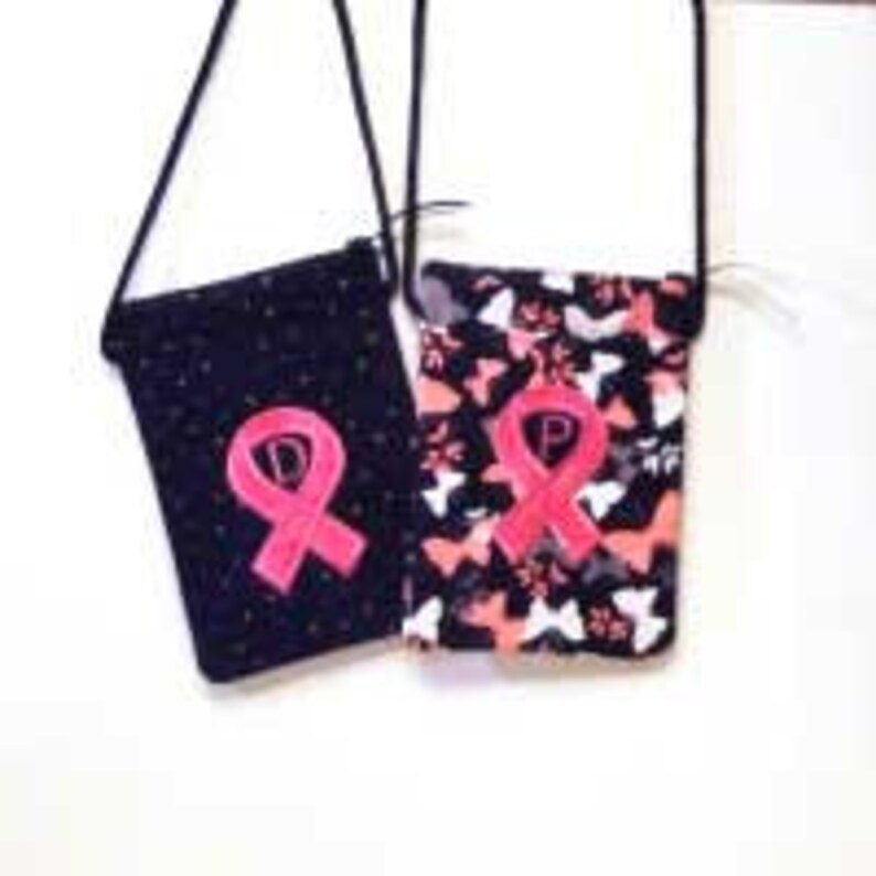 Puede incluir: Dos bolsos bandolera de tela negra con bordado de cinta rosa y estampado de mariposa blanca. Una bolsa tiene un fondo negro con lunares blancos, la otra tiene un estampado de mariposa blanca sobre un fondo negro.
