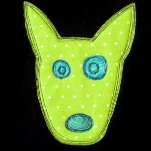 May include: A green felt applique of a dog's face with white polka dots. The dog has blue eyes and a blue nose.