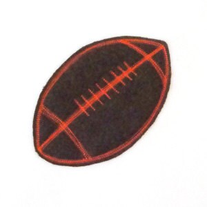 May include: A brown leather football patch with red stitching. The patch is about 2 inches long and 1 inch wide.
