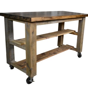 May include: A rustic wooden kitchen island with two shelves and wheels. The island has a natural wood finish and is made of reclaimed wood.