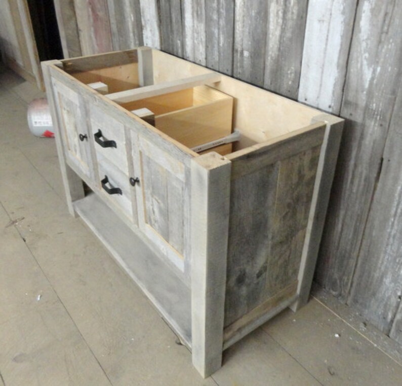 May include: A grey wooden bathroom vanity with two drawers and a lower shelf. The vanity is made from reclaimed wood and has a rustic look.