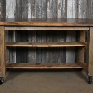 May include: A rustic wooden kitchen island with two shelves and wheels. The island is made of reclaimed wood and has a natural finish.