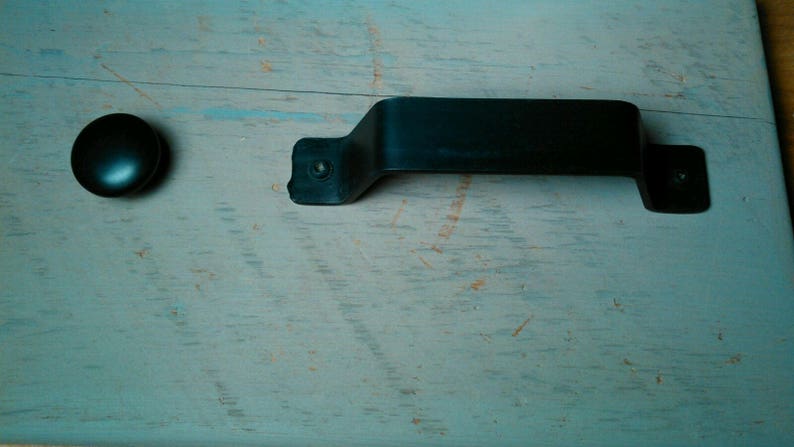 May include: A black metal door handle with a rounded knob on a light blue wooden surface.