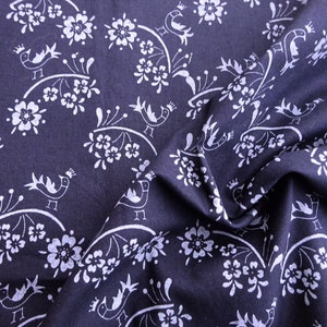 May include: Navy blue fabric with a white floral and bird pattern. The design features stylized birds wearing crowns perched on curved branches with flowers. The fabric is folded, showing texture and depth.