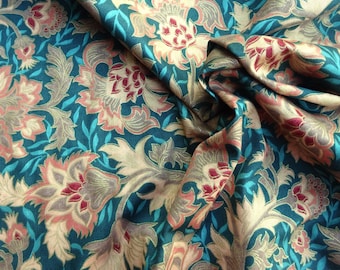 May include: Close-up of a teal fabric with a floral pattern. The design features large, stylized flowers in shades of pink, cream, and gray, set against a backdrop of teal and accented with turquoise leaves. The fabric is draped, showing its texture and folds.