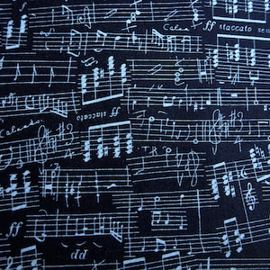 May include: Close-up of a black background covered in white musical notation. Handwritten musical notes, clefs, and symbols are scattered across the surface. Some text includes "ff staccato semp" and "For Calado."