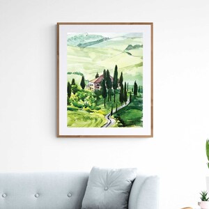 May include: Watercolor painting of a green landscape with a winding road leading to a small house. The painting is framed in a light wood frame.