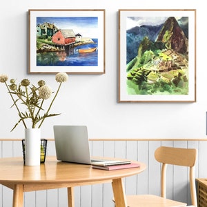 Puede incluir: Dos acuarelas enmarcadas en una pared blanca. La pintura de la izquierda muestra una casa roja en una costa con un peque&ntilde;o bote en el agua. La pintura de la derecha muestra una monta&ntilde;a verde con una estructura de piedra en el lado.