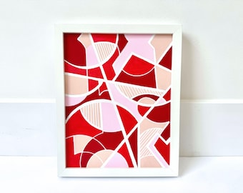 May include: Abstract painting with geometric shapes in shades of red, pink, and white. The painting is framed in a white frame.