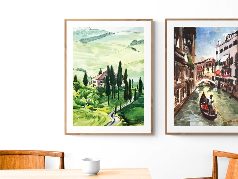 May include: Two watercolor paintings in wooden frames. The painting on the left depicts a green rolling hillside with a small house and trees. The painting on the right shows a canal in Venice with a gondola and a gondolier.