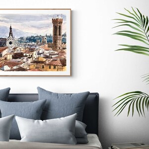 May include: A watercolor painting of a cityscape with a tall tower and a church in the background. The buildings are painted in shades of brown, orange, and yellow, and the sky is a light blue with gray clouds.