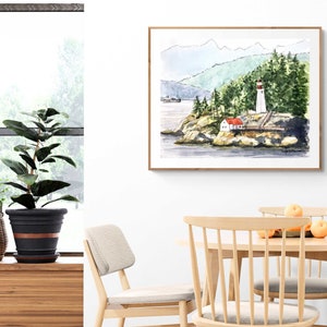 May include: Watercolor painting of a lighthouse on a rocky island with a red roofed house in the foreground. The lighthouse is white with a red roof and a red stripe. The painting is framed in a light wood frame.