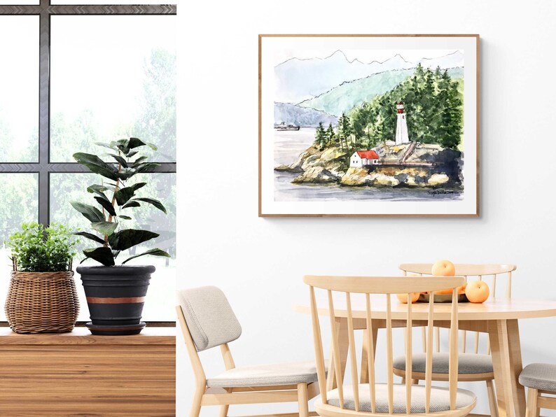 May include: Watercolor painting of a lighthouse on a rocky island with a red roofed house in the foreground. The lighthouse is white with a red roof and a red stripe. The painting is framed in a light wood frame.