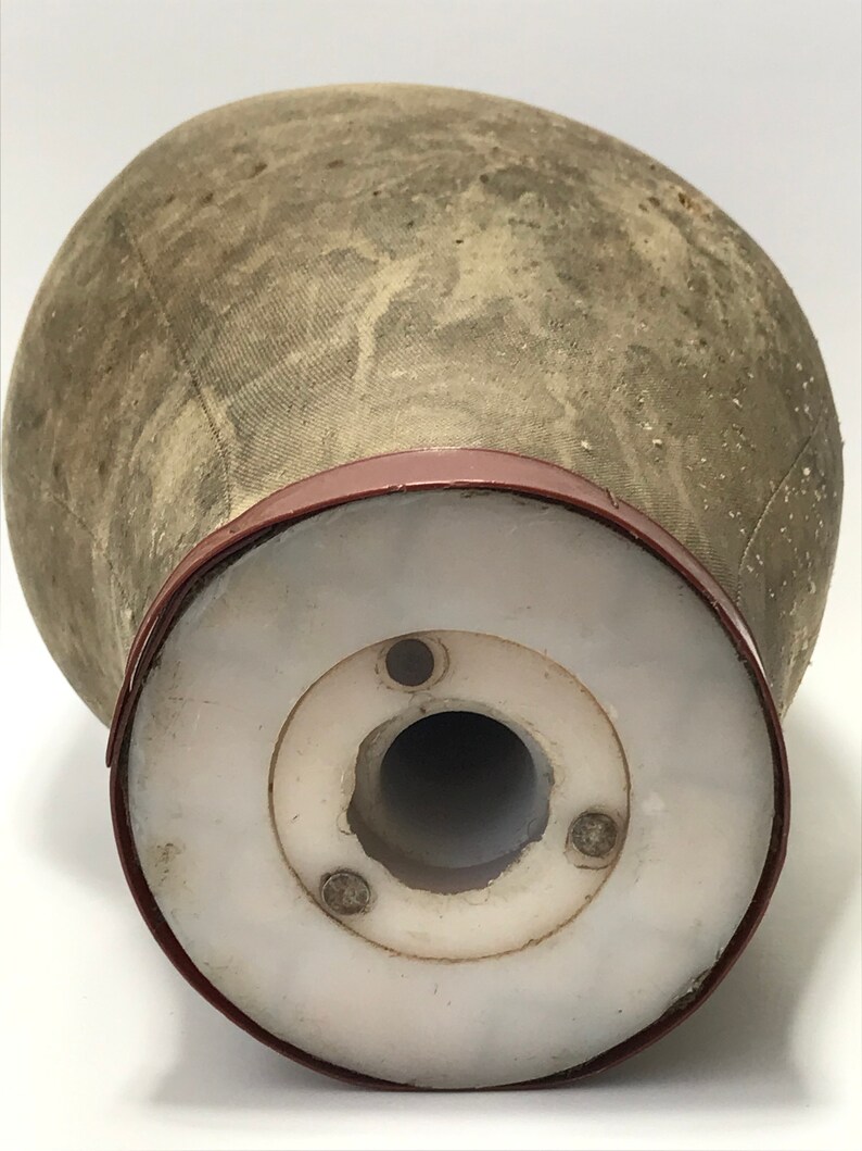 May include: A vintage, gray fabric mannequin head with a red plastic base. The base has a white plastic insert with a hole in the center.
