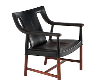 May include: Black leather armchair with a curved back and armrests. The chair has a dark wood frame and legs. The design is mid-century modern, with a focus on clean lines and comfort. The chair is suitable for a living room or office.