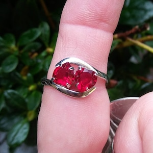 May include: A silver ring with two red heart-shaped gemstones.