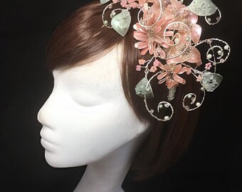 Puede incluir: Un peine para el cabello delicado con flores rosas y verdes, perlas y alambre plateado. El peine está diseñado para ser usado en el cabello como un accesorio decorativo.