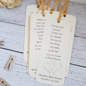 Pu&ograve; includere: Un set di segnalibri rettangolari in carta color avorio con angoli arrotondati, ciascuno dotato di un nastro dorato sulla parte superiore. I segnalibri riportano testo stampato dal libro Love You Forever di Robert Munsch e un cuore.