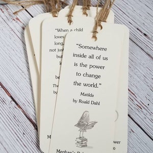 Pu&ograve; includere: Un set di segnalibri rettangolari in carta color crema con angoli arrotondati e cordini in spago marrone. Ogni segnalibro riporta la citazione "Somewhere inside all of us is the power to change the world." di Roald Dahl e un'illustrazione.