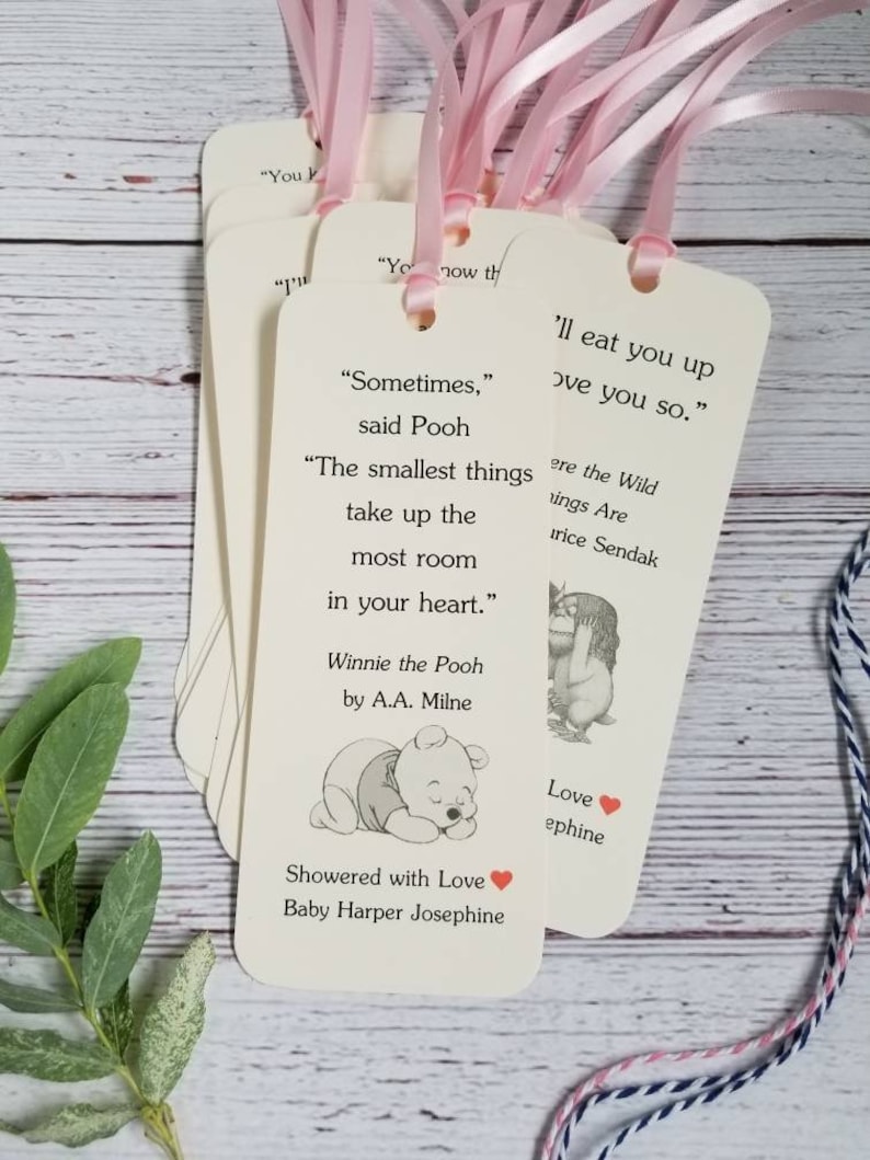 Pu&ograve; includere: Un set di segnalibri rettangolari in carta color crema, ciascuno dotato di un foro nella parte superiore con un nastro rosa chiaro. I segnalibri presentano citazioni letterarie stampate, illustrazioni di personaggi e testo personalizzato.