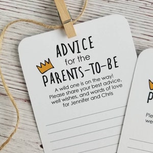 May include: A white card with black text that reads "Advice for the Parents-to-Be". A yellow crown is above the text. The card has lined spaces for writing advice for the new parents. A wild one is on the way! Please share your best advice, well wishes, and words of love for Jennifer and Chris.