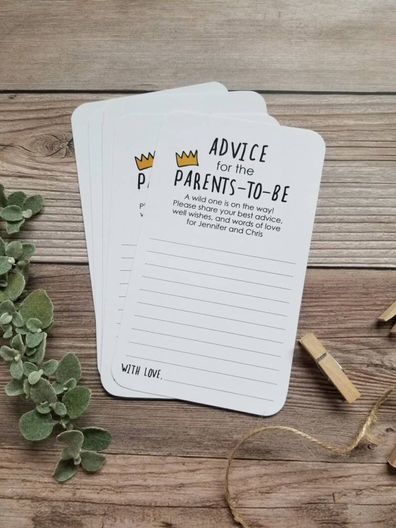 May include: A set of white cards with black and gold text. The cards feature a crown icon and the text "Advice for the Parents-to-Be". The text continues with "A wild one is on the way! Please share your best advice, well wishes, and words of love for Jennifer and Chris". The cards have lines for writing and the text "With Love."
