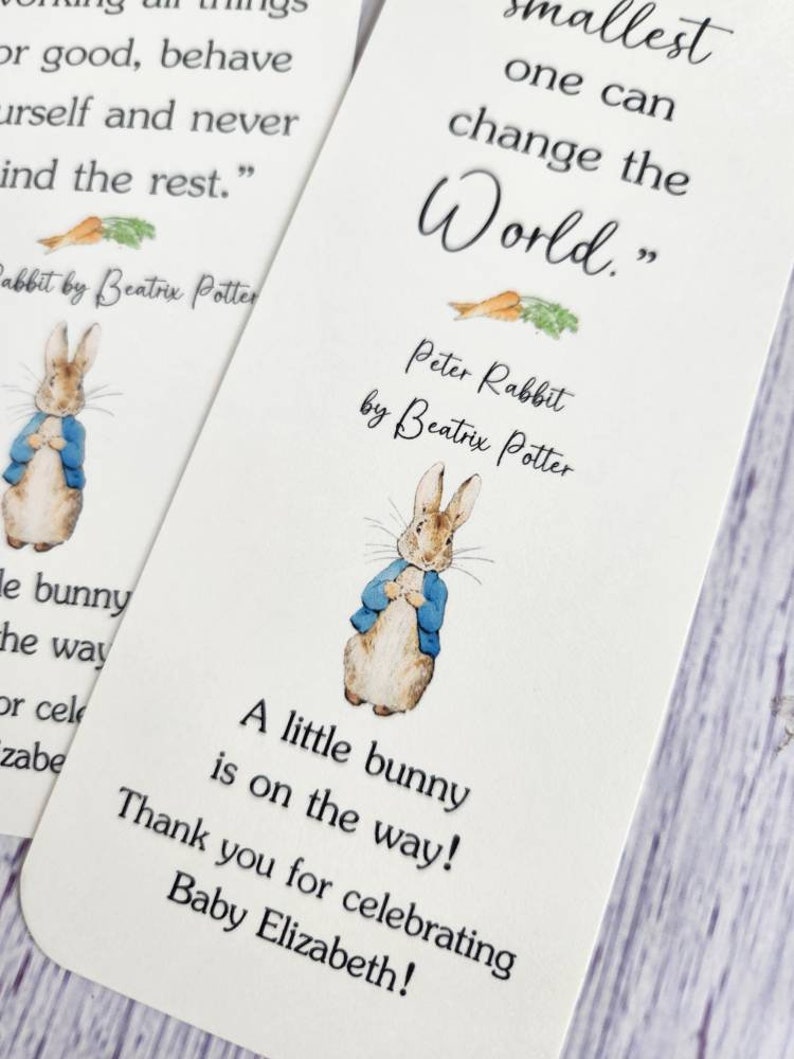 May include: A white card with a Peter Rabbit illustration and the quote "The smallest one can change the world."  The card also includes the text "Peter Rabbit by Beatrix Potter" and "A little bunny is on the way! Thank you for celebrating Baby Elizabeth!"